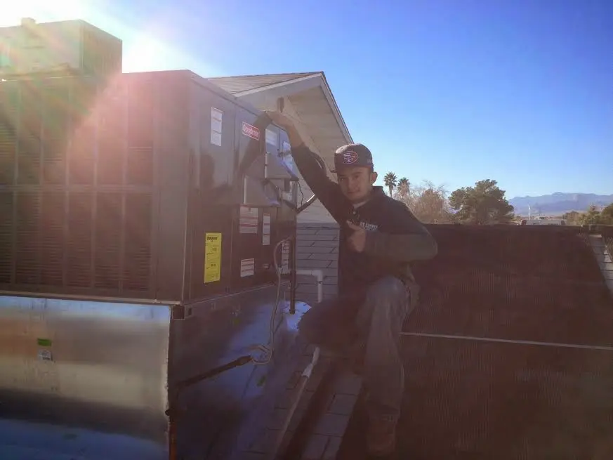 HVAC technician performing Air Duct Cleaning on a rooftop unit in DeSoto